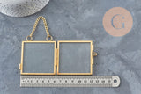 Cadre photo double articulé en verre et métal doré avec chaînette de suspension, posé sur un fond gris texturé.