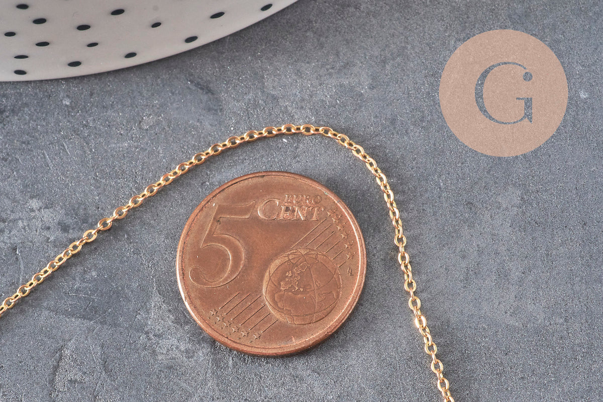 Chaîne forçat fine de 1mm en laiton brut doré posée sur une pièce de 5 centimes pour montrer l'échelle.