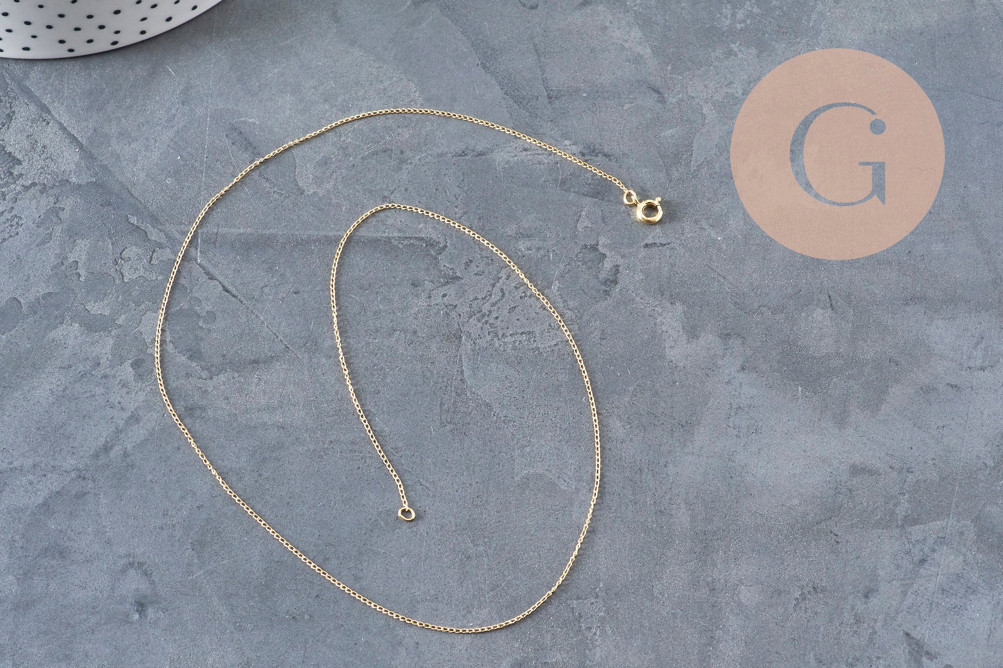 Collier chaîne fine dorée gold-filled 14K de 45.7cm avec fermoir, sur fond gris.