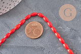 Fil de perles ovales en bambou de mer rouge imitation corail, 8x4mm, présenté avec une pièce de 5 centimes pour l'échelle.
