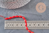 Fil de perles ovales en bambou de mer rouge imitation corail, 8x4mm, mesuré sur une règle en métal.